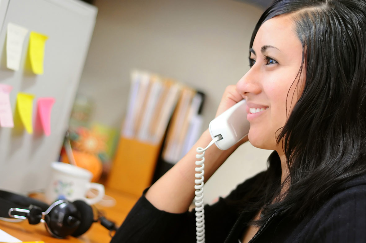 Young woman at the office, talking on the phone