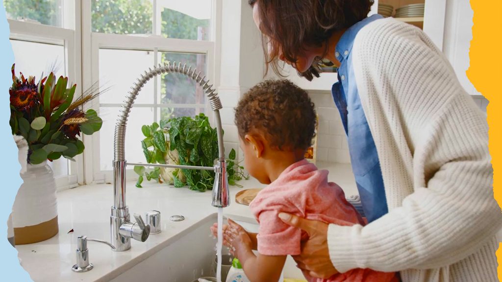 Adult helping child wash their hands in the sink